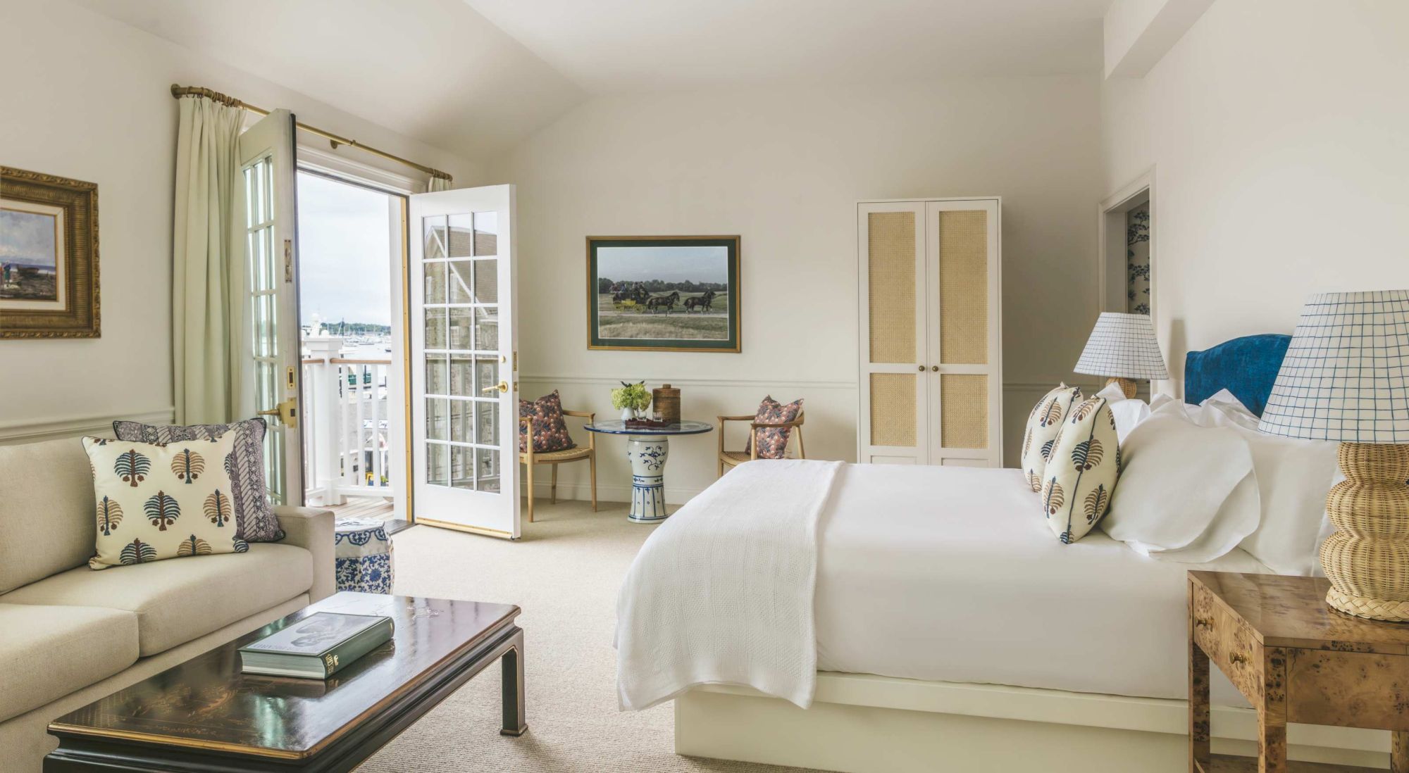 A well-lit bedroom with a double bed, sofa, coffee table, and patio doors leading outside. The room is decorated with soft, neutral colors.