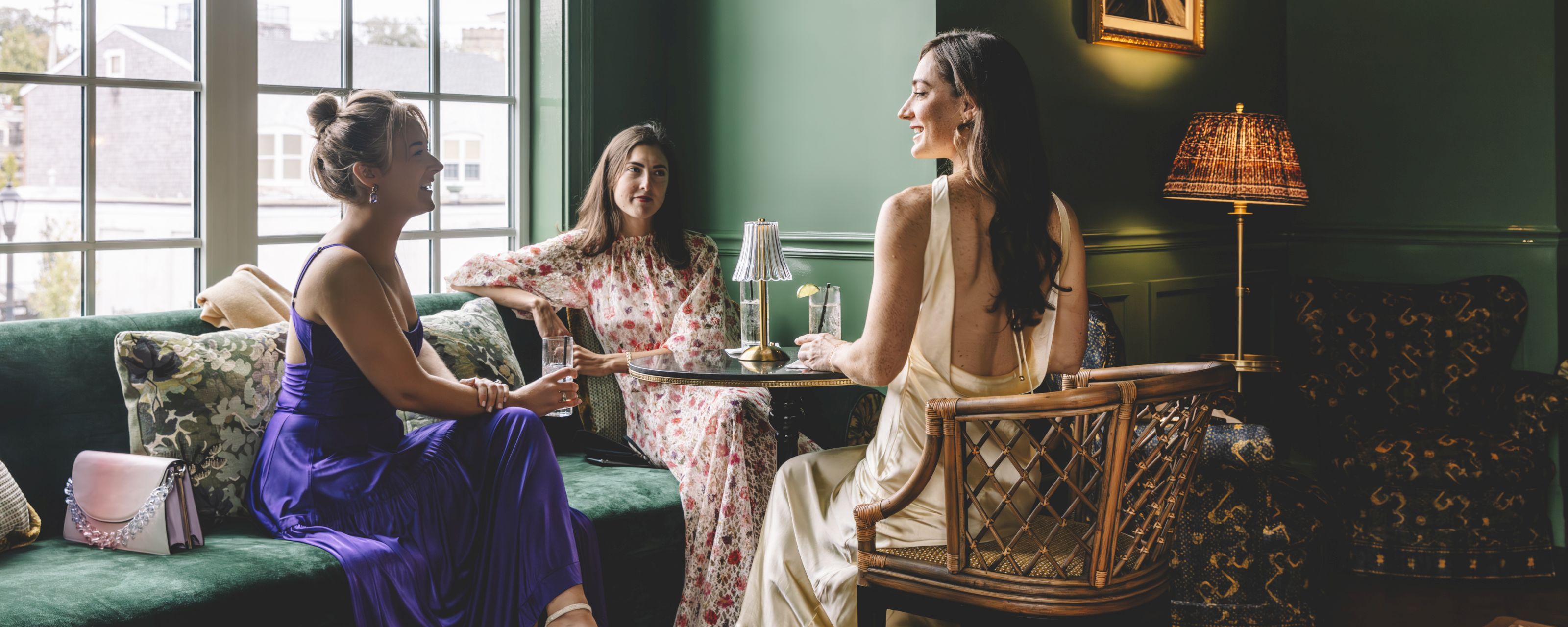 Three women sitting in a lounge with green walls and furniture