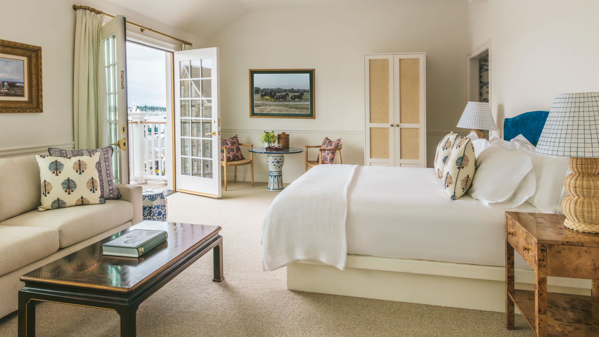 A wide view of a hotel room with a bed, sofa, coffee table, and balcony door.