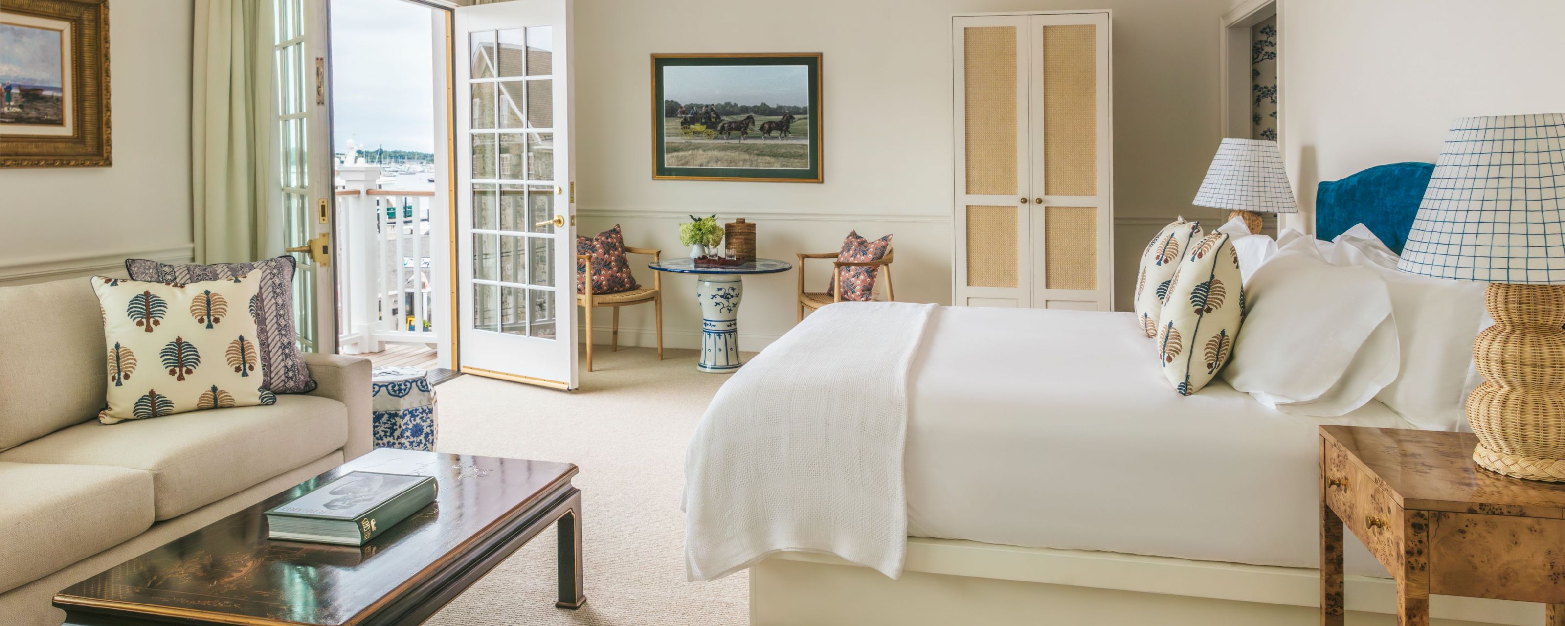 A wide view of a hotel room with a king-sized bed, sofa, and balcony