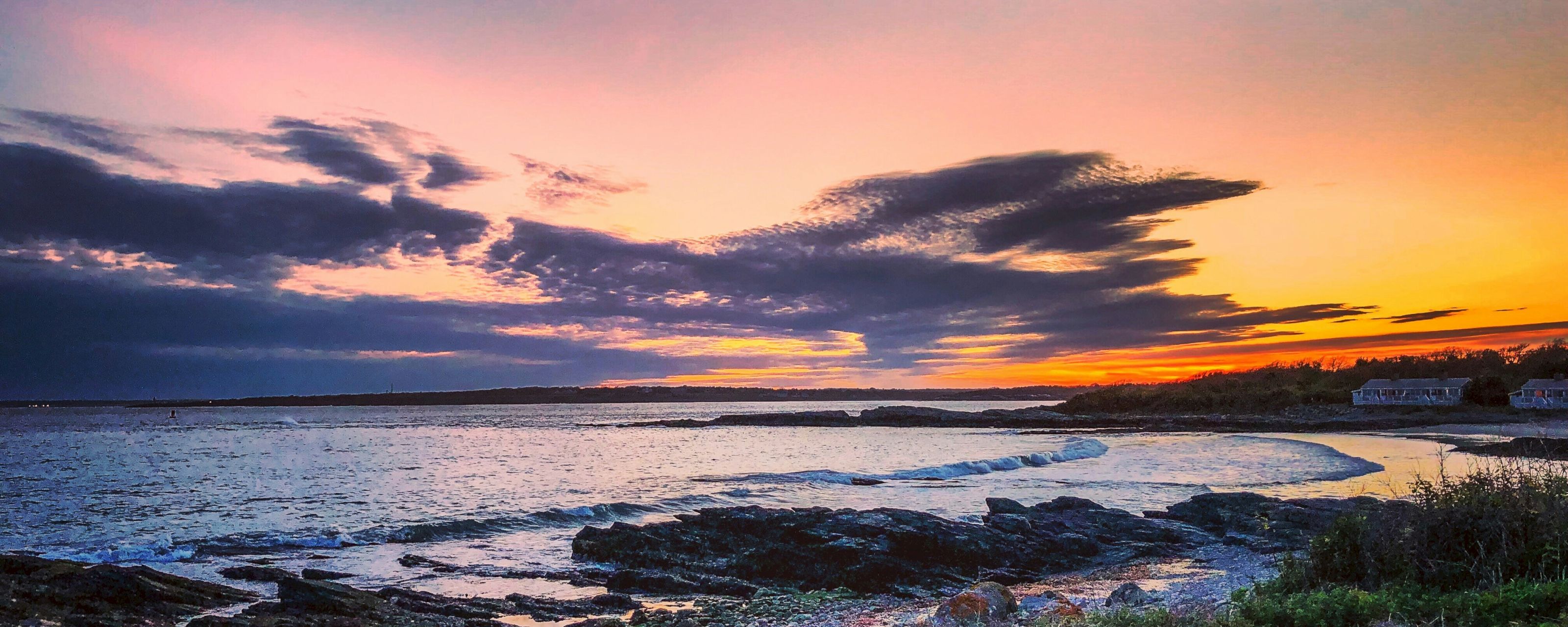 A serene beach scene at sunset with a vibrant sky and calm waters.