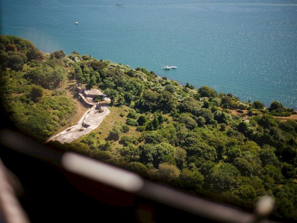 An aerial view of The Cliff Walk—a lush, green landscape next to the Atlantic Ocean and a boat visible on the water.