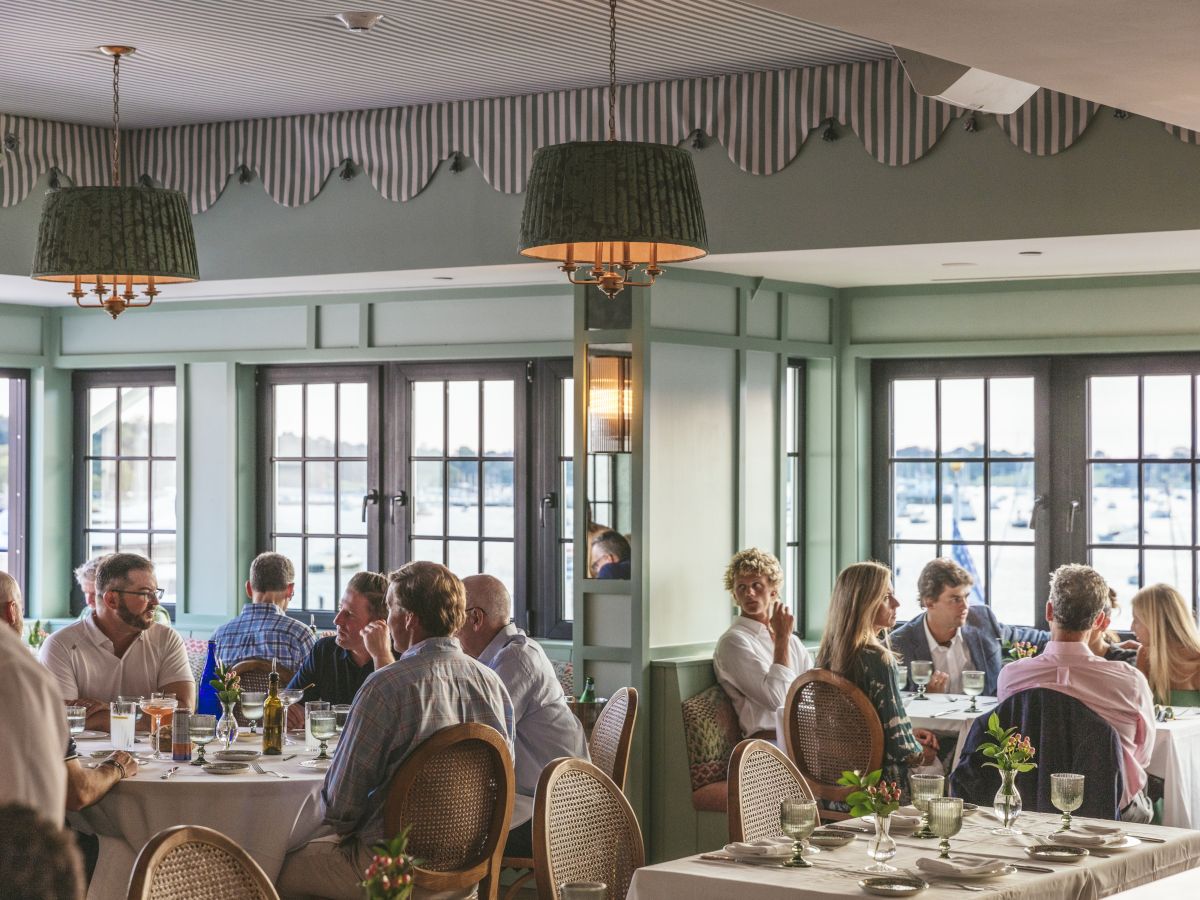 People dining at Flora restaurant: a cozy, elegantly decorated restaurant with large windows and a view of the Newport Harbor.