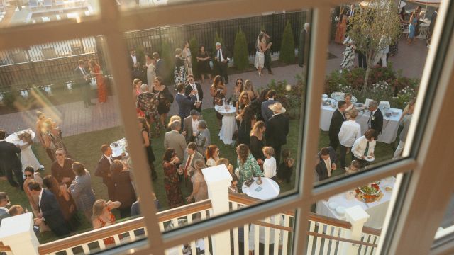 A high-angle view of a crowded outdoor event space with people mingling and tables set up for food and drink.